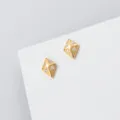 Detailopname van prachtige geometrische ruitvormige oorknopjes met diamant op een witte blok. - Grote Ruit Stijl (M08104) / Set van 1 paar / Goud