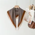 Close-up view of the vintage brown geometric print square scarf hanging on a wooden hanger. - XPM-10