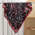Detailed view of the red and black abstract pattern square silk scarf draped on a metal rod. - Striped - Red
