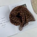 Close-up detail of the brown polka dot chiffon scarf, elegant accessory for summer styling. - Brown Polka Dot