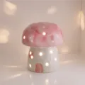 Pink ceramic mushroom night light with warm glowing cutouts for cozy bedroom desk decor and ambiance. - Pink