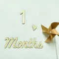Detail shot of wooden monthly milestone number 1 and months prop with paper pinwheel. - 1+Months+Heart Windmill
