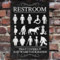 Closeup detail of funny novelty restroom hanging sign on brick wall, creative decor plaque. - Black Bathroom Door Signs