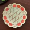 Vintage ceramic plate featuring cute red apple patterns, green speckled base, scalloped rim. - 5.8-Inch Ruffled Plates - Retro Apple