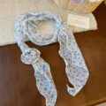 Gedetailleerd overzicht van witte chiffon halsdoek met blauwe bloemen en chique knoop. - Wit Blauw Floraal