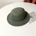 Vue détaillée d'un chapeau feutré vert foncé à calotte plate posé sur une table blanche. - M (56-58cm) / Gris