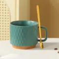 Detailed close-up of a ceramic coffee mug with unique hammer texture and a matching gold spoon. - Dark Green + Spoon