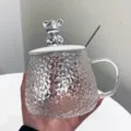 Glass coffee cup detail showcasing textured hammer pattern body and cute silver bear lid. - 401-500ml / Silver Bear