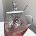 Detail shot of clear hammered glass mug with cute silver bunny lid and spoon for drinks. - 401-500ml / Silver Rabbit