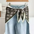 Vue rapprochée d'un jean bleu clair associé à un foulard en soie à motif floral noué à la taille. - Motif en croix - Vert foncé