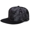 Primer plano de gorra hip hop negra con visera plana, logotipo K y tela con estampado de grafitis. - Ajustable / Gorra negra de visera plana - Letra K