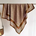 Detail view of a brown silk-like square scarf featuring a geometric Greek key pattern - QQ-3
