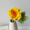 Detailed view of handmade crochet yellow rose flower with green leaves in a white ceramic vase. - Gradient Orange