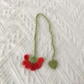 Handmade crochet yarn bookmark detail, cute red flower green leaf design on white fabric background. - Red Flower Bookmark