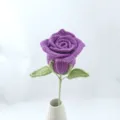 Handmade crochet purple rose flower ornament with green leaves and stem in white ceramic vase. - Purple