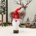 Vista dettagliata della coperta per bottiglia di vino natalizia in maglia con cappello gnomo. - Modello MG-02 con fiocchi di neve