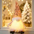 Pink Christmas gnome plush toy with sequin hat and warm LED lights for holiday desktop decor. - Pink