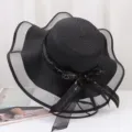 Detailed close-up view of elegant black summer straw hat with mesh brim and ribbon. - One Size / Black