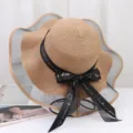 Detailed view of the wide brim straw hat featuring elegant black mesh and ribbon bow decoration. - One Size / Khaki