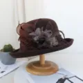 Gros plan et détail du chapeau en feutre de laine marron avec résille délicate et fleurs de plumes. - Réglable / Café Foncé