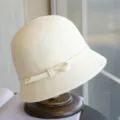 Detail view of the elegant cream wool cloche hat, featuring a delicate side bow and ribbon trim. - Adjustable / Cream