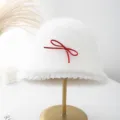 Nahaufnahme des weißen Plüsch Fischerhuts mit roter Schleife, warmer Lammwollmütze im Winter. - M (56-58cm) / Weiß