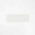 Detail view of a white floral lace headband, showing intricate wavy edge and elastic texture. - White