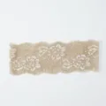 Nahaufnahme von beiger elastischer Spitzenborte mit filigranem Blumenmuster für Heimwerken. - Hellbeige