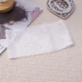 Detailed view of the white vintage paisley lace headband, showing delicate floral and wavy edges. - White