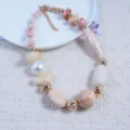 Close-up detail of resin irregular bead necklace with gold metallic accents and pastel tones. - Off White