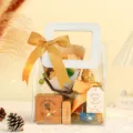 Detalle de bolsa de regalo de PVC transparente con ramo, caja de vela perfumada y lazo. - S / Bolsa Transparente con Asa Blanca + Cinta Dorada