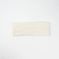 Detailed view of beige knitted paisley headband, soft elastic hair accessory for women. - Milky White