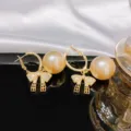 Raffinierte Perlen Schleife Ohrringe Detailansicht, goldenes Design mit glänzenden Diamanten. - Champagner