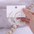 Gros plan de boucles d'oreilles créoles en perles de cristal avec fil doré sur carton blanc. - Blanc Cristal