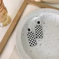 Close-up detail of chic black and white checkered geometric earrings displayed on a tray. - Rectangle