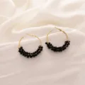 Gros plan détaillé de boucles d'oreilles créoles dorées élégantes ornées de perles de cristal. - Noir Cristal