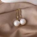 Elegante vergoldete Perlen-Ohrringe mit funkelnden Zirkonia-Steinen im Detail. - Kupfer-Mikropavé mit weißen Perlen