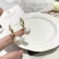 Gold hoop earrings with dangling iridescent pearl charms, elegant and chic jewelry detail view. - White Pearl Hoops