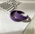 Detailaufnahme von retro lila geflockten Creolen, die eine einzigartige Textur zeigen. - Lila