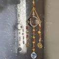 Close-up detail shot of crystal suncatcher with moon and star charms casting beautiful light prisms. - Man in the Moon Yellow
