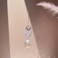 Close-up detail of hanging crystal suncatcher with rainbow light refraction and pink feather. - Pink