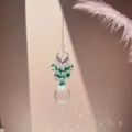 Close-up detail of hanging crystal suncatcher prism with heart top and green beads in sunlight. - Dark Green