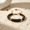 Nahaufnahme Detailaufnahme des Natur-Tigerauge-Edelstein-Perlenarmbands mit goldenem Brückenanhänger. - Tigerauge-Stein-Armband
