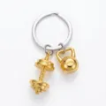 Gym fitness dumbbell and kettlebell metal keychain pendant detail view for sports lovers. - Gold
