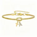 Primo piano del bracciale catena serpente dorata con nodo d'amore, croce e ciondolo con lettera. - Bracciale Nodo Concentrico Croce Strass Stile A / Oro