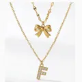 Collana multistrato dorata con ciondolo a fiocco e lettera F scintillante di strass. - Stile a Doppio Strato con Lettera Iniziale F e Fiocco / Oro
