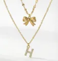 Collana dorata a doppio strato con fiocco chic e ciondolo con lettera H in strass scintillanti. - Stile a Doppio Strato con Lettera Iniziale H e Fiocco / Oro