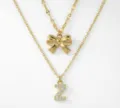Collana doppia dorata con grazioso ciondolo a fiocco e lettera Z scintillante con strass. - Stile a Doppio Strato con Lettera Iniziale Z e Fiocco / Oro