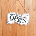 Vintage wooden open sign detail showing classic lettering and natural rope hanger texture. - White