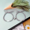 Nahaufnahme von Partner-Armbändern mit magnetischem Herzanhänger und grauem geflochtenen Seil. - 1 Paar / Grau